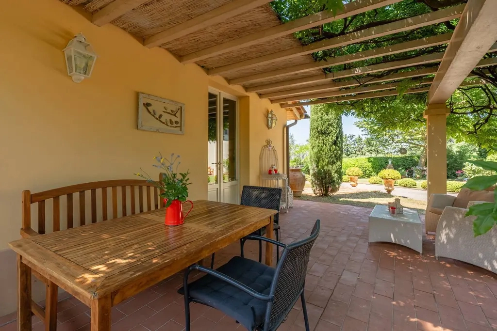 Patio esterno arredato con tavolo, sedie e comode poltrone